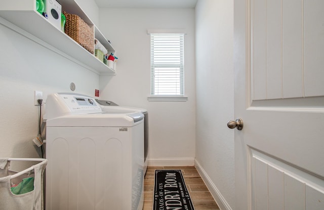 laundry area with laundry area, baseboards, wood finished floors, and washer and dryer