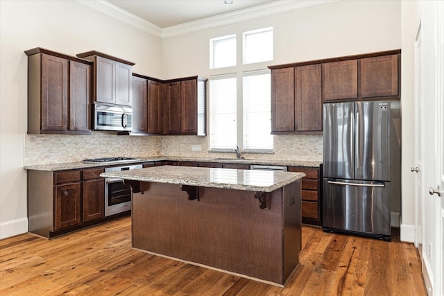 9443 Fannin St, Houston, TX 77045 - kitchen with stainless steel appliances, dark brown cabinets, a center island, crown molding, and a breakfast bar area