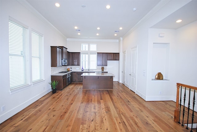 9443 Fannin St, Houston, TX 77045 - kitchen featuring appliances with stainless steel finishes, dark brown cabinetry, light countertops, crown molding, and a center island
