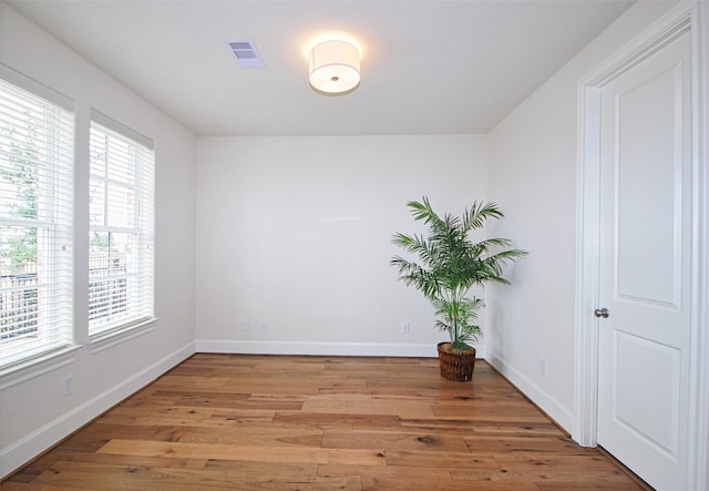 unfurnished room featuring baseboards, light wood finished floors, and visible vents