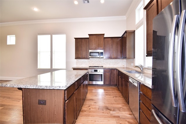 9443 Fannin St, Houston, TX 77045 - kitchen featuring stainless steel appliances, a sink, a kitchen island, crown molding, and light stone counters