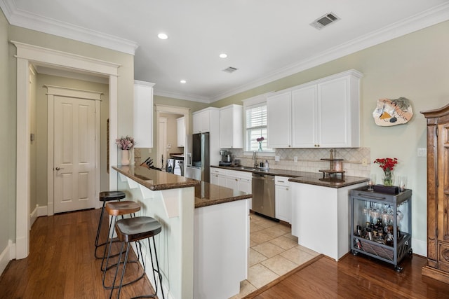 8 Latitude Ln, Galveston, TX 77554 - kitchen with a kitchen bar, visible vents, appliances with stainless steel finishes, tasteful backsplash, and white cabinetry