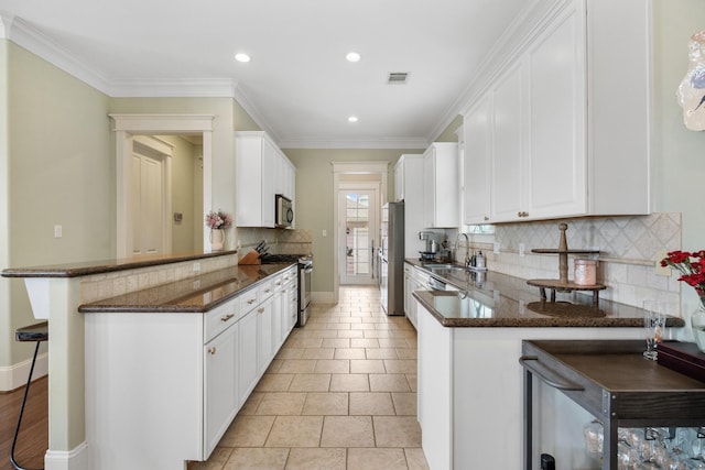 8 Latitude Ln, Galveston, TX 77554 - kitchen featuring visible vents, a peninsula, a kitchen bar, a sink, and stainless steel appliances