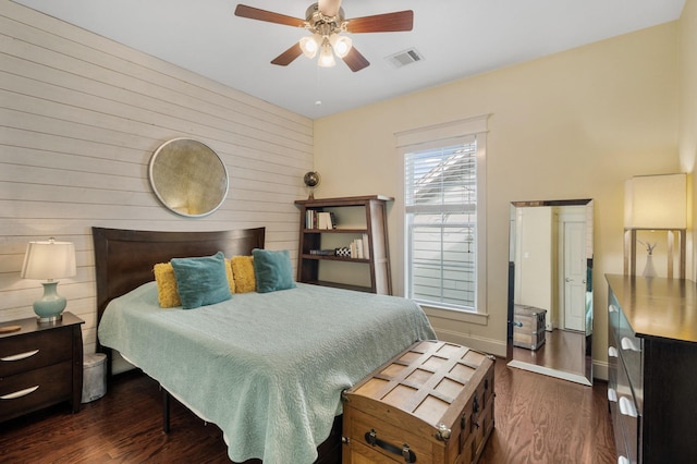 8 Latitude Ln, Galveston, TX 77554 - bedroom featuring visible vents, wood walls, dark wood-style flooring, baseboards, and ceiling fan