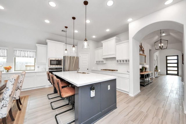 kitchen featuring plenty of natural light, arched walkways, appliances with stainless steel finishes, and light countertops