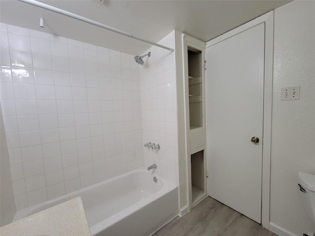 bathroom with shower / bathing tub combination, toilet, and wood finished floors