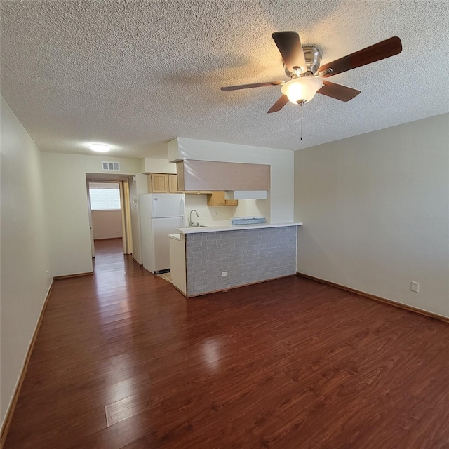 unfurnished living room with a sink, a ceiling fan, a textured ceiling, and dark wood-type flooring