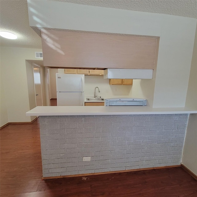 kitchen featuring visible vents, freestanding refrigerator, dark wood-style floors, light countertops, and a sink