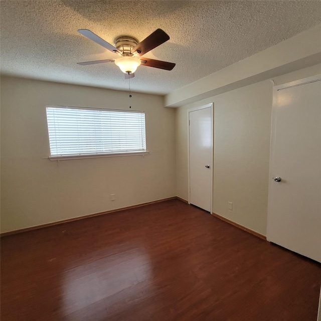 empty room featuring baseboards, a textured ceiling, dark wood-style flooring, and ceiling fan