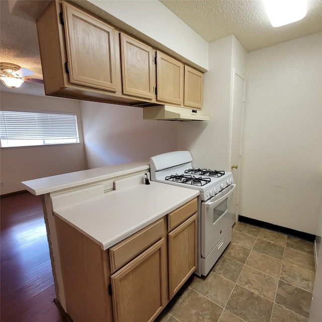 kitchen featuring a ceiling fan, a textured ceiling, light brown cabinetry, white gas range oven, and under cabinet range hood