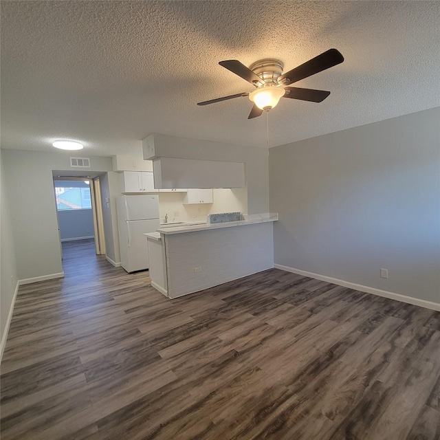 unfurnished living room with a ceiling fan, dark wood-style floors, and a textured ceiling