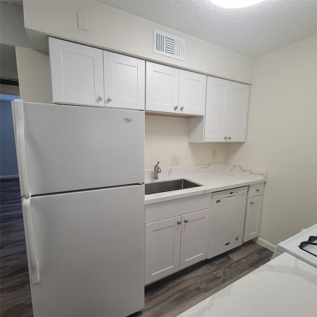 kitchen featuring white cabinets, a sink, white appliances, dark wood-type flooring, and visible vents