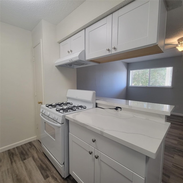 kitchen featuring dark wood-type flooring, a textured ceiling, white cabinetry, under cabinet range hood, and white gas range oven