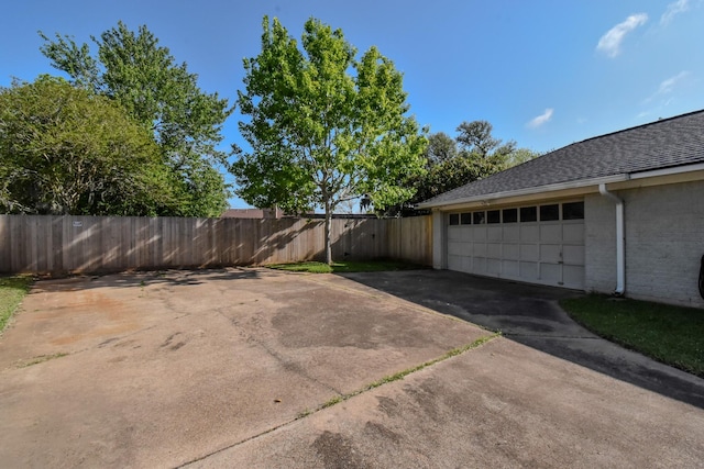 view of patio with fence, concrete driveway, and a garage