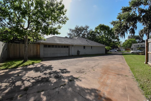view of home's exterior with an attached garage, aphalt driveway, and fence