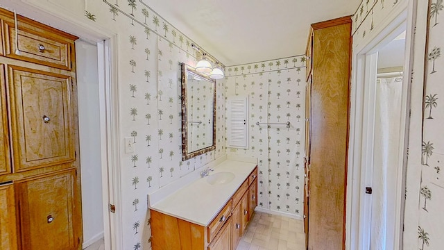 bathroom featuring vanity, baseboards, and wallpapered walls