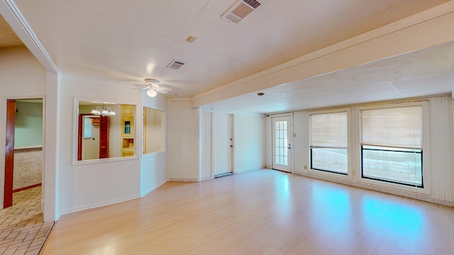 empty room with light wood-style floors, baseboards, ceiling fan with notable chandelier, and visible vents
