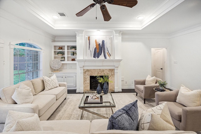 living area featuring ceiling fan, visible vents, wood finished floors, and a tray ceiling