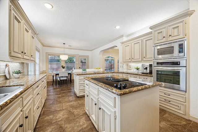 kitchen with cream cabinets, appliances with stainless steel finishes, arched walkways, a peninsula, and backsplash