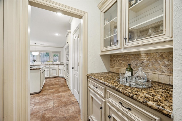 bar with backsplash, crown molding, stainless steel oven, and stone finish floor