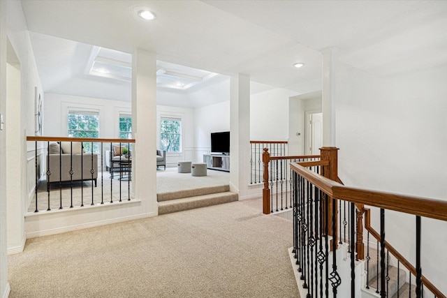 interior space with carpet flooring, recessed lighting, a tray ceiling, and an upstairs landing