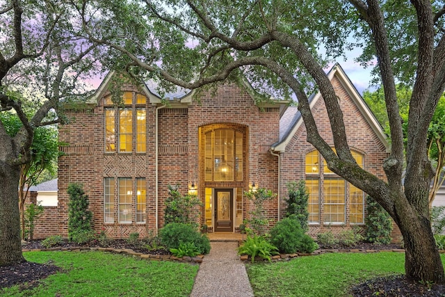 tudor home featuring a yard and brick siding