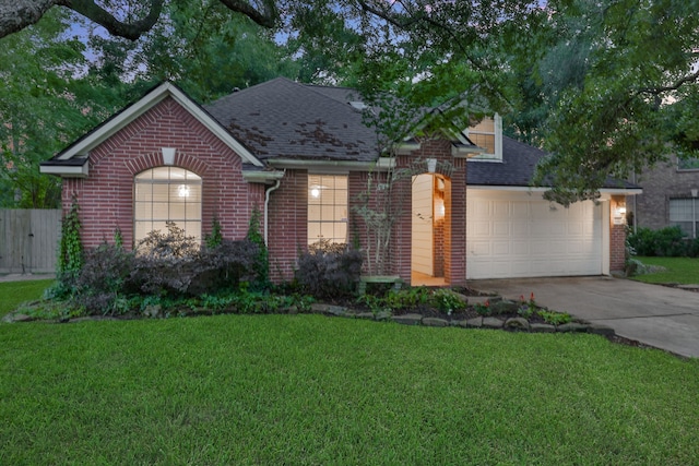 view of front of home featuring roof with shingles, concrete driveway, a front yard, and brick siding