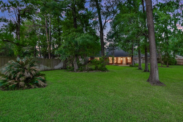 yard at dusk featuring fence private yard