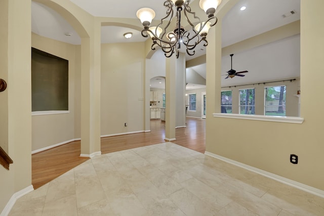 unfurnished room featuring arched walkways, baseboards, visible vents, and ceiling fan with notable chandelier