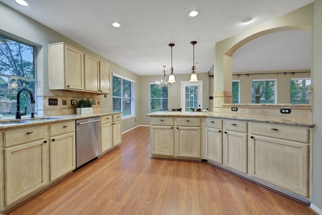 kitchen featuring light brown cabinetry, a sink, light wood-style floors, decorative backsplash, and stainless steel dishwasher