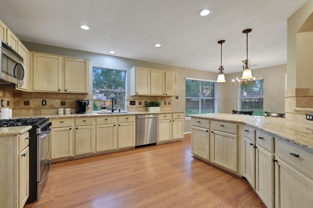 kitchen with a sink, decorative backsplash, stainless steel appliances, and a wealth of natural light