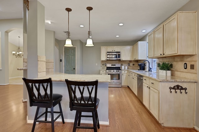 kitchen featuring a peninsula, light wood-style floors, a breakfast bar area, a sink, and appliances with stainless steel finishes