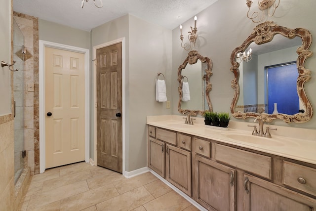 bathroom with double vanity, a textured ceiling, a tile shower, and a sink