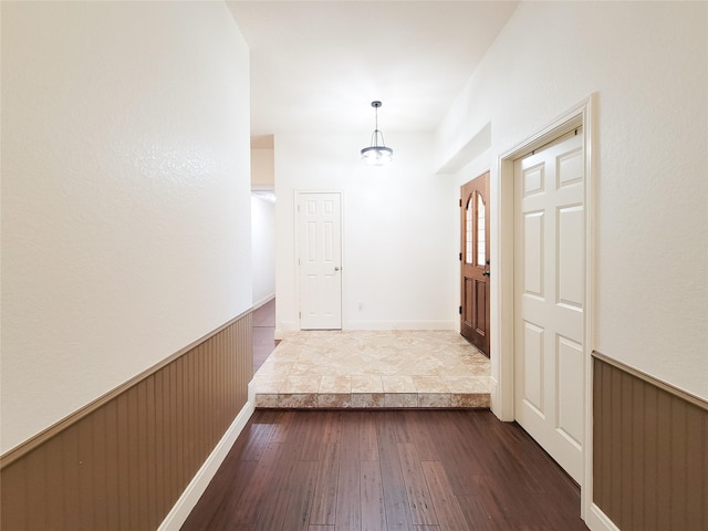 hallway featuring wood-type flooring and wainscoting