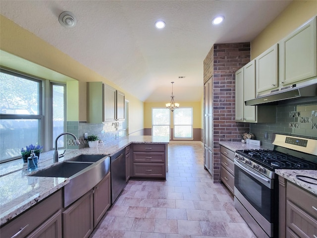 kitchen featuring a peninsula, under cabinet range hood, appliances with stainless steel finishes, backsplash, and a notable chandelier