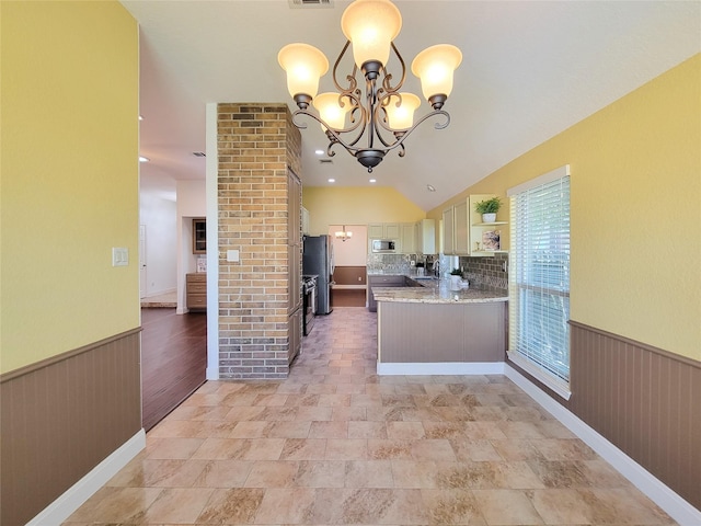 kitchen featuring open shelves, appliances with stainless steel finishes, wainscoting, an inviting chandelier, and light stone countertops