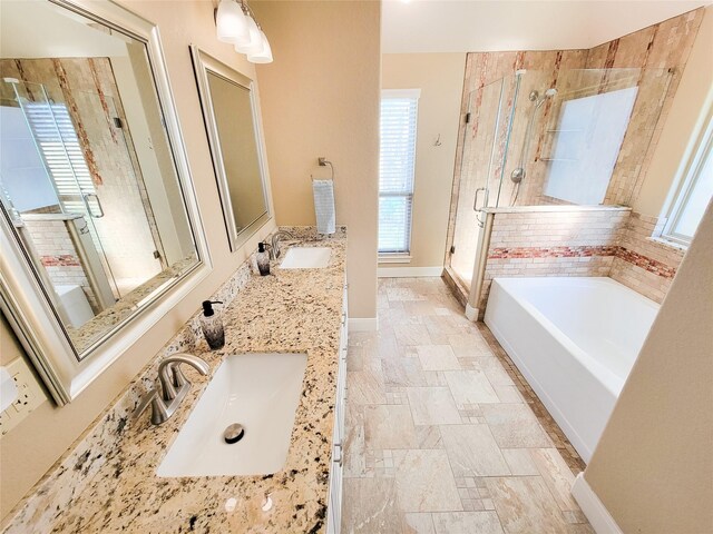 bathroom featuring stone tile flooring, a sink, a bath, and a stall shower