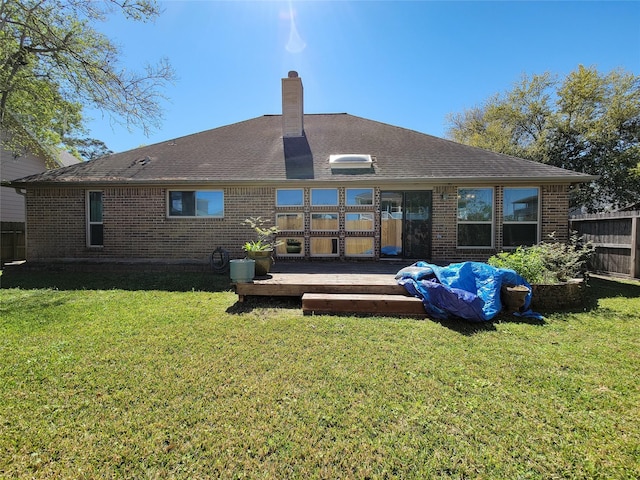 rear view of property with fence, a wooden deck, a yard, and brick siding