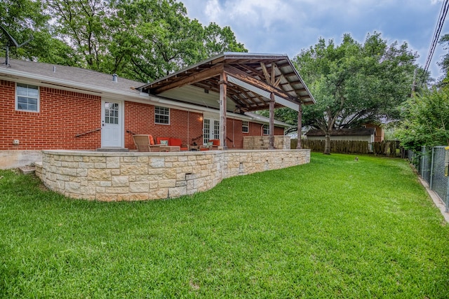 back of house featuring a lawn, a fenced backyard, brick siding, and a patio