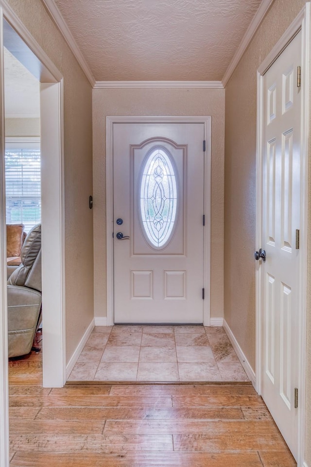 entrance foyer featuring light wood-style floors, baseboards, and crown molding