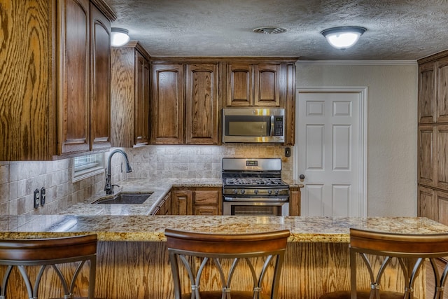1302 Woodson Ln, Brenham, TX 77833 - kitchen with stainless steel appliances, a sink, backsplash, a textured ceiling, and a kitchen breakfast bar