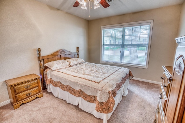bedroom with a ceiling fan, baseboards, and light carpet