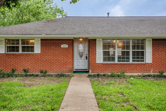 view of front of house featuring brick siding, roof with shingles, and a front lawn