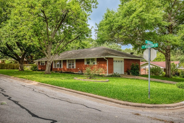 ranch-style home featuring fence, an attached garage, brick siding, a front yard, and concrete driveway