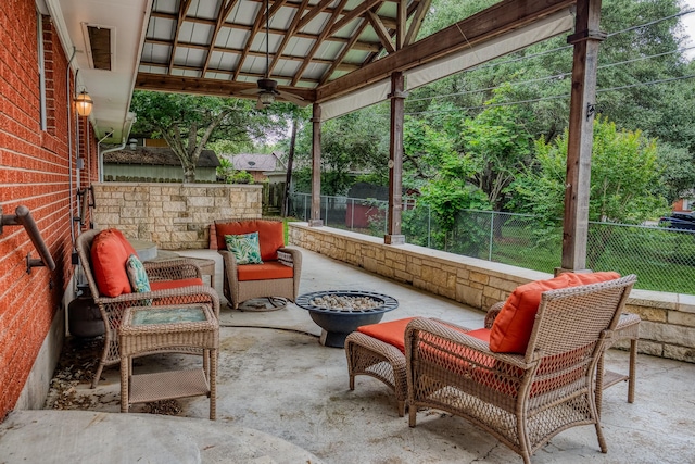 view of patio featuring a fenced backyard, ceiling fan, and an outdoor living space with a fire pit