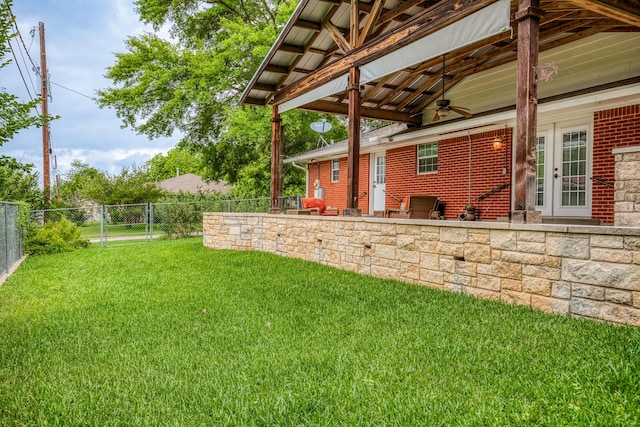 view of yard featuring ceiling fan, fence, and french doors