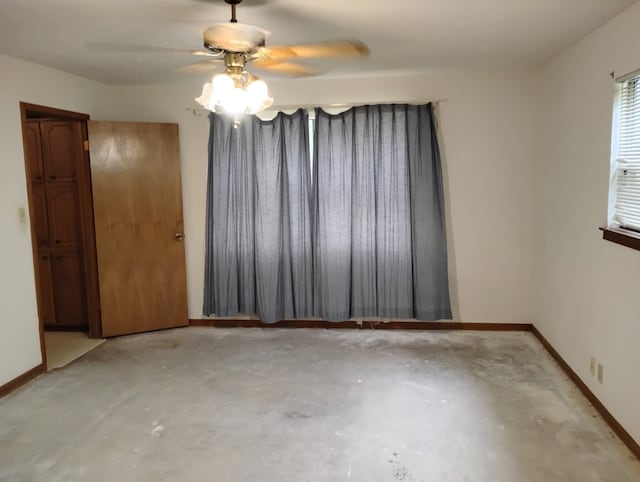 spare room with a ceiling fan, baseboards, and concrete floors