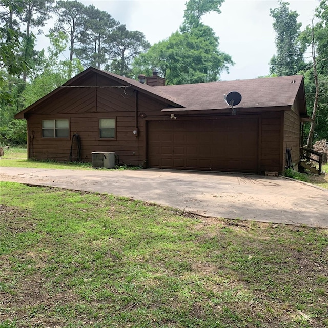 view of front facade with a front lawn, a chimney, central AC unit, an attached garage, and driveway