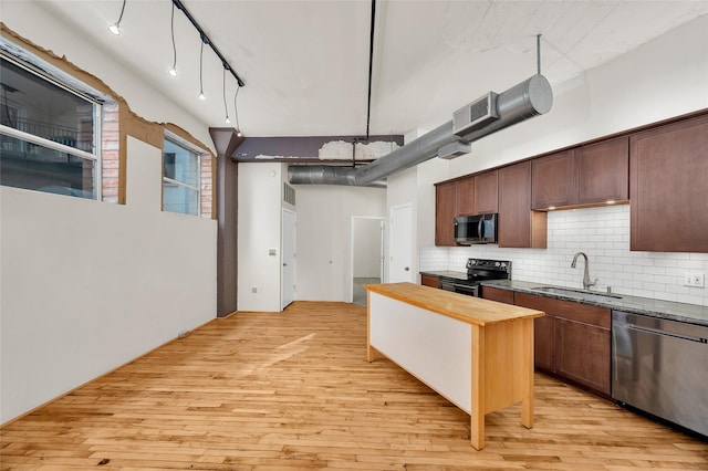 kitchen featuring backsplash, a sink, light wood finished floors, butcher block counters, and stainless steel appliances