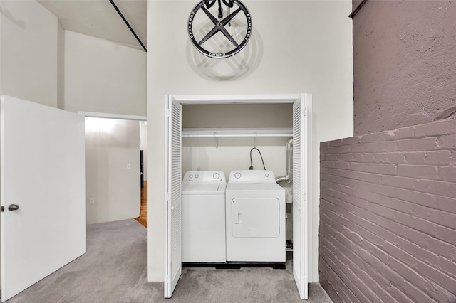 laundry area featuring laundry area, light colored carpet, washing machine and dryer, and brick wall
